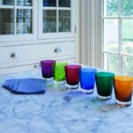 MOSA√èQUE tumblers set. Handcrafted using traditional glassblowing techniques, these glasses are the perfect gift! Available in a set of 6 in 6 different colors. The tableware has a simple silhouette that is precise and elegant. The understated shape of the tumblers makes their use appropriate for any and all drinking experiences: as a water or fruit juice glass, or mixed in with Baccarat clear crystal bar sets. The hand-blown MOSA√èQUE tumblers are cased in clear crystal, and are available in a vast array of cheerful colors in this set: orange, blue, purple, moss, green, and Baccarat‚Äôs signature ruby red crystal. The interplay of light with the smooth surface and the colored crystal makes for a radiant table, and a compelling soir√©e.