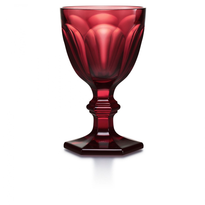 Baccarat HARCOURT 180 years red glass. On the occasion of its 180th anniversary, the HARCOURT glass, a timeless icon, is exclusively adorned in golden red. A real object of desire. Limited and numbered edition of 180 pieces. The star of glasses and the glass of the stars, the HARCOURT glass symbolizes splendor and radiance. With its perfect silhouette resting on its hexagonal foot and its six facets capturing light, it alone embodies the craftsmanship and glamorous lifestyle of Baccarat. In a golden red version, presented in a box engraved with the