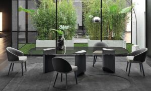 WEDGE DINING TABLE by NENDO, designed in 2019. Bulky look created by the solid sculptural masses of the semi-circular legs of wedge contrasts with the lightweight feet, which culminate in an oblique chisel tip shape. The entire volume of the table, hosting the large top, appears to become weightless and leans lightly on the tips of the legs, challenging the law of gravity.