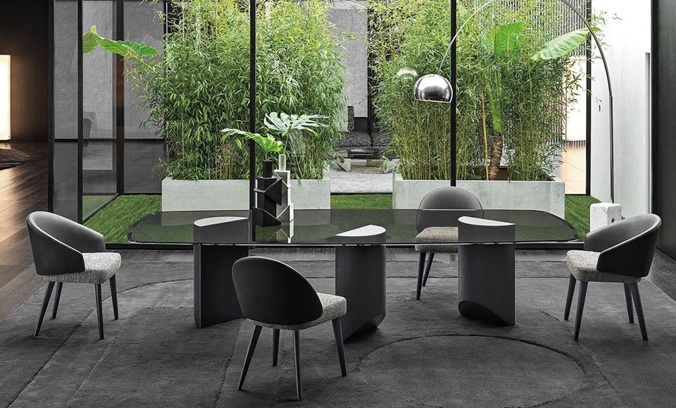 WEDGE DINING TABLE by NENDO, designed in 2019. Bulky look created by the solid sculptural masses of the semi-circular legs of wedge contrasts with the lightweight feet, which culminate in an oblique chisel tip shape. The entire volume of the table, hosting the large top, appears to become weightless and leans lightly on the tips of the legs, challenging the law of gravity.