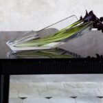 DIVA vase. Its unexpected and avant-garde silhouette reinvents expectations of design and reconfigures the possibilities for creating a compelling floral arrangement. The open cylinder of clear crystal cradles the floral assembly and keeps it carefully in place, yet still gives the plants plenty of room to breathe. Moreover, this vase makes it possible to place a bouquet on the table and still be able to see the person sitting on the opposite side. It is both a conversation piece and a work of impeccable craftsmanship.  / available in 2 sizes