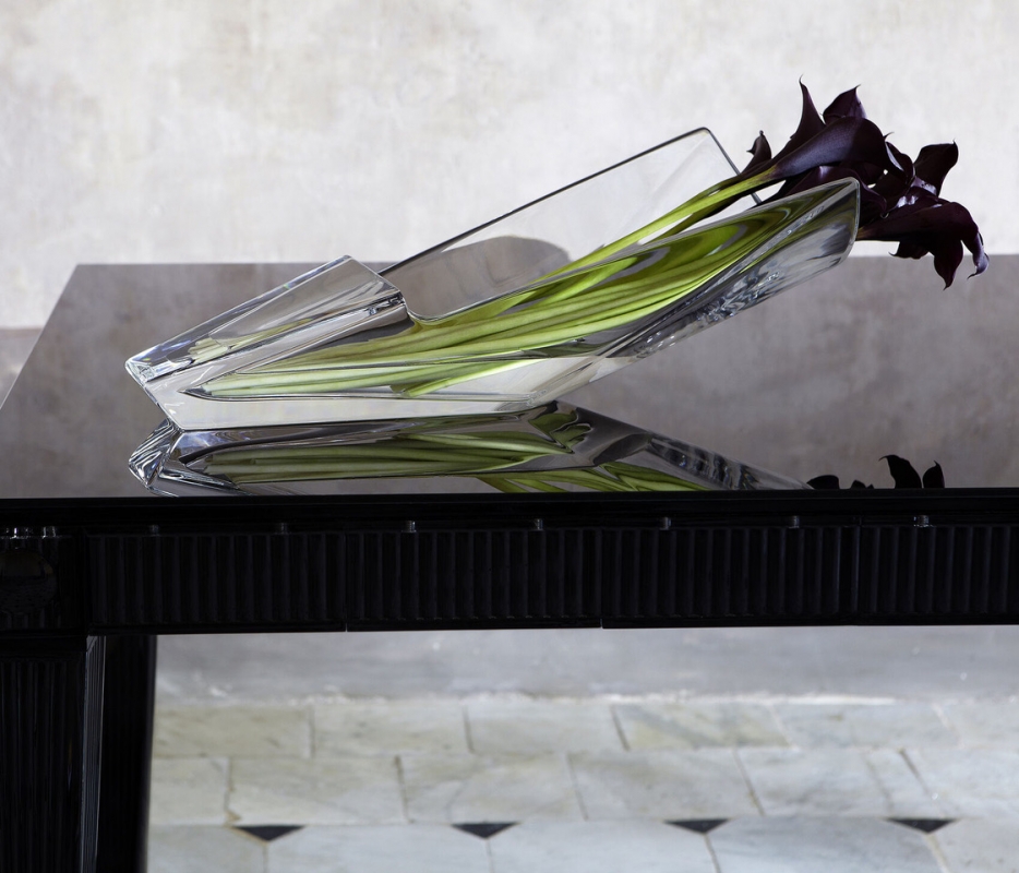 DIVA vase. Its unexpected and avant-garde silhouette reinvents expectations of design and reconfigures the possibilities for creating a compelling floral arrangement. The open cylinder of clear crystal cradles the floral assembly and keeps it carefully in place, yet still gives the plants plenty of room to breathe. Moreover, this vase makes it possible to place a bouquet on the table and still be able to see the person sitting on the opposite side. It is both a conversation piece and a work of impeccable craftsmanship.  / available in 2 sizes