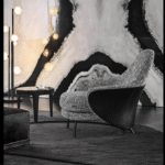 ANGIE armchair by GAMFRATESI STUDIO, designed in 2019. The GAMFRATESI STUDIO, signing the design, worked on the idea of contrast, emphasising it and juxtaposing the stiff frame of the saddle hide element with the softness of the upholstered part, which can also be seen on the back, so setting the scene for interesting colour combinations of saddle hide and fabric. The legs are in pewter-coloured die-cast aluminium and a unique bow-shaped frame connects the feet at the rear, emphasising the curve of the saddle hide body.