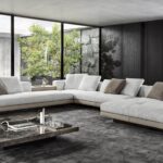 CONNERY seating system by RODOLFO DORDONI, designed in 2020. With its geometric rigour, the base creates an original contrast with the softness of the seat, conceived as a single cushion punctuated by light stitching defining the width of the seat ‚Äì 83 or 68 cm ‚Äì and with the structure of the backrest and armrest, covered in channelled goose down padding. The backrest and armrest form a single volume, with a 45¬∞ split in the corner.