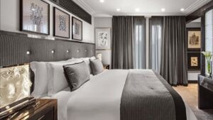 LALIQUE SUITE by PATRICK HELLMANN at HOTEL PRINCE DE GALLES, PARIS. DESIGNER PATRICK HELLMANN has swathed the entire suite in a mosaic of mostly black and gold to bring that Art Deco look to life, and then layered it with texture, such as sculptural side tables and blonde wood furniture, to provide some balance. HELLMANN also selected some iconic crystal pieces for the renovation, like the SEVILLE CHANDELIER‚Äîfirst designed by MARC LALIQUE in 1947‚Äîthat hangs over the curvy black-and-gold staircase that leads up to the bedroom.