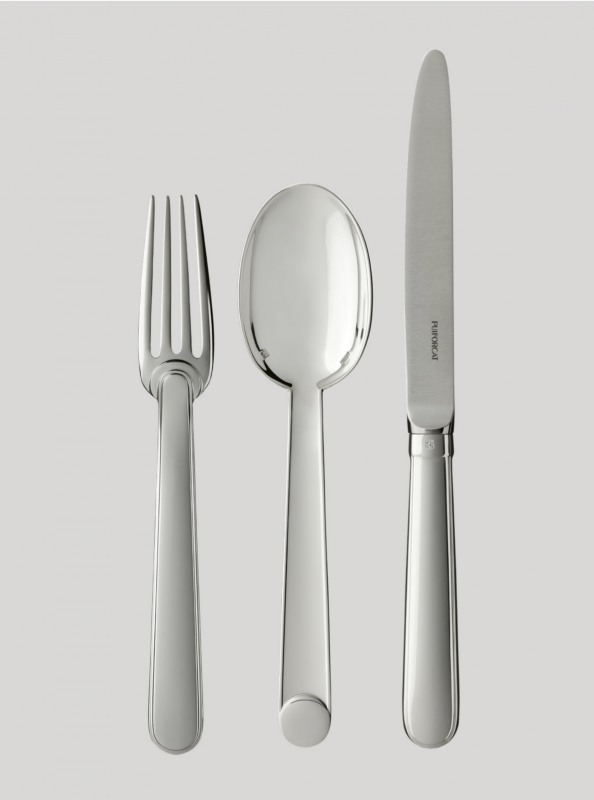 NORMANDIE cutlery collection. Linking Le Havre to New York, the famous ocean liner Normandie embodied Art Deco and its French artists and was honored at the 1925 Exposition Universelle. This timeless cutlery, designed by JEAN PUIFORCAT in 1934, graced the tables of the dining rooms in first-class suites. Now available in silver-plated metal, the elegant silhouette, with its smooth surfaces and delicate curves accentuated by an ornamental disk, is also offered in a line of table accessories.