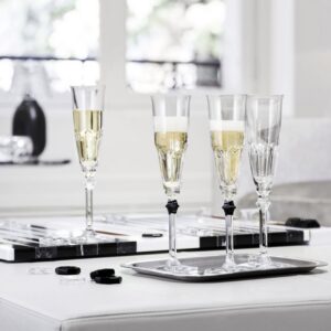 HARCOURT EVE champagne glasses. Adorned with a black button, the EVE champagne glasses gives a touch of daring and perfect elegance to your table in a subtle play of contrasts between light and shadow