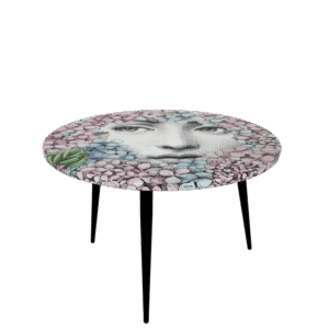 TABLE ORTENSIA. THE ROUND¬†TABLE¬†IS DRESSED WITH THE D√âCOR ORTENSIA (HYDRANGEA), A RECENT REINVENTION BY BARNABAFORNASETTI. THIS MOTIF ENRICHES THE SERIES TEMA E VARIAZION (THEME AND VARIATIONS) WITH A REINTERPRETATION OF LINA CAVALIERI ICONIC FACE PEEKING AT THE OBSERVERS BEHIND COLOURFUL AND JOYFUL HYDRAGEAS, THE SAME PLANTS THAT HAVE SURROUNDED CASA FORNASETTI IN MILAN FOR 60 YEARS. THE TABLE IS PRINTED, LACQUERED AND PAINTED BY HAND.
