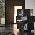 PAGE by RODOLFO DORDONI, designed in 2019. With its decidedly sculptural presence and the contrasting textures of the interiors and exteriors of its three volumes, the page bookcase is inspired by works of modern art. Its misaligned blocks, set one on top of the other also call to mind contemporary architectures. Fully swivelling, it is characterised by volumes in the form of parallelepipeds, with outer edges in mocha-coloured wenge wood and glossy painted warm grey-coloured interiors, and it stands on a circular base with a glossy pewter-coloured finish. A bold piece of furniture that is sure to turn heads, ideal in any part of the room, including the centre. In addition to its function as a bookcase, page can also be used as a contemporary display cabinet to accommodate objects or as a bar cabinet.