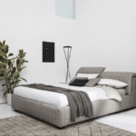 PORTLAND bed designed by Daniele Lo Scalzo Moscheri. The idea underpinning this product comes from reclaimed padded seats from exclusive luxury vintage trains and features soft vertical quilting that tempers the grandeur of the generously voluminous design. When the headboard is opened, PORTLAND offers a practical functional container unit for storage. The item is available with three versions of the feet in wood and one in metal with the option of choosing the look and height from the ground that suits the customer best. The PORTLAND bed is available with a fixed bed base or container unit. Can be upholstered in fabric or leather.