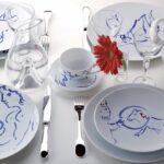 PORCELAIN TABLEWARE COLLECTION POUR IDA. LIMITED EDITION OF THE ORIGINAL WEDDING SERVICE CREATED IN 1952 BY MARC CHAGALL IN VALLAURIS FOR THE WEDDING OF HIS DAUGHTER. EACH PIECE BEARS A DIFFERENT DRAWING REPRODUCED WITH BRUSH STROKES EXECUTED BY HAND. THE IMAGES EVOKE THE POETRY, TENDERNESS, FANTASY AND HUMOR DERIVED FROM THE RICHNESS OF THE PAINTER'S CREATIVE UNIVERSE THROUGH HIS MOST FAVORITE THEMES: THE WOMAN, THE COUPLE, THE FLOWERS, THE CIRCUS AND ANIMALS.