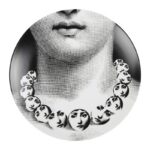 TEMA E VARIAZIONI WALL PLATE - NO. 107. THIS TEMA E VARIAZIONI WALL PLATE IS A TRULY UNIQUE PIECE OF ART FROM THE WORLD FAMOUS FORNASETTI BRAND. BEAUTIFULLY CRAFTED FROM PORCELAIN IT DEPICTS THE FACE OF OPERA SINGER LINA CAVALIERI DUPLICATED ONTO A CIRCULAR NECKLACE WORN BY HERSELF. CLASSICALLY INFLUENCED YET CONTEMPORARY IN STYLE, IT IS A STUNNING EXAMPLE OF THE DESIGNER‚ÄôS ICONIC STYLE & IT MAKES A FABULOUS GIFT IDEA FOR ANY OCCASION. DIAMETER:26CM
