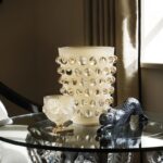 MOSSI XXL vase designed by REN√â LALIQUE.  The kaleidoscopic effect of the MOSSI Vase is both a stroke of creative genius and a feat of technical mastery. REN√â LALIQUE designed this flagship piece in 1933. His original choice of material was plain glass, which the company has transformed into the vibrant intensity of crystal. A genuine interior design accessory of modernity, the MOSSI plays on the contrast between the brilliance of its cabochons and the frosting of its base. It has been recently reinterpreted in this extra large size.