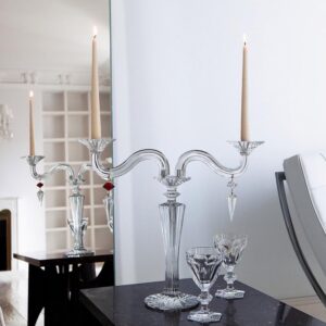 MILLE-NUITS candelabra. The bevel-cut arms of the candelabra, amidst which stand two decorative crystal swirls, glitter luminously. Each candelabra arm is adorned with dangling arrowhead-shaped crystals that catch the light in a scintillating manner. Candles nestle within crystal candleholders shaped like blooming daffodils. The MILLE NUITS candelabra is a sumptuous item, made in two-, three-, or five-light versions; also available in gold. Hurricane shades, available separately, emphasize every candle flicker and intensify the luminosity. Designed for Baccarat by MATHIAS, MILLE NUITS is a reference to the 1001 Tales of The Arabian Nights. The MILLE NUITS collection also encompasses chandeliers, stemware, and home d√©cor.