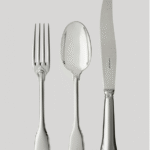 NOAILLES cutlery collection. Since the 16th century, Augsburg, Bavaria has been renowned for the unparalleled savoir-faire of its silversmiths. For Louis-Victor Puiforcat, a keen collector of high-quality pieces, an early design from this Bavarian city inspired the production of this sterling silver cutlery. The apparent simplicity of the design is contrasted by the refinement of every detail: the curved contour, the handle outlined with a fine thread, the elegant flame- shaped button at the base of the fork and spoon