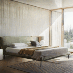 FLUFF bed designed by DANIELE  LO SCALZO MOSCHERI. Fluff stands apart for its sobriety and linear simplicity. We upholstered a well-proportioned lightweight frame and made it one with the headboard, forming a single body attached with invisible seams. The mattress seems suspended in air although it rests on a slight yet sturdy structure set on slender metal feet. The edges of the whole bed have been trimmed with a fabric band detail which accentuates the superior textile workmanship of the product.