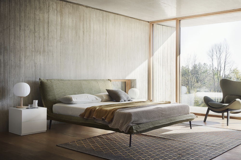 FLUFF bed designed by DANIELE  LO SCALZO MOSCHERI. Fluff stands apart for its sobriety and linear simplicity. We upholstered a well-proportioned lightweight frame and made it one with the headboard, forming a single body attached with invisible seams. The mattress seems suspended in air although it rests on a slight yet sturdy structure set on slender metal feet. The edges of the whole bed have been trimmed with a fabric band detail which accentuates the superior textile workmanship of the product.