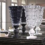 NEW ANTIQUE vase by MARCEL WANDERS STUDIO. This exquisite hand-blown clear crystal vase mounted on a stylish white marble base is available in a limited edition of 99 numbered pieces. MARCEL WANDERS STUDIO has drawn inspiration from classic pieces of decorative art and from his own Baroque world in creating a new collection of vases which is appropriately named NEW ANTIQUE. Each vase is blown and decorated with deep geometric cuts before being mounted on a black Italian marble base, much like a trophy. This clear crystal vase, decorated inside with black lacquer and criss-cross bevel cuts, is available in a limited edition of 99 numbered pieces signed Baccarat and MARCEL WANDERS STUDIO. It is an exquisite piece that will lend sumptuous splendour to any room.
