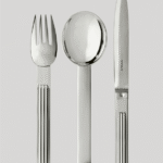 DEAUVILLE cutlery collection. At the time of expanding seaside tourism, elegant villas and the renowned construction of the celebrated sea bath cabins, DEAUVILLE  was rich in architectural influences that inspired JEAN PUIFORCAT. In 1937, he designed a cutlery collection with a solid, slightly curved handle and three rectilinear grooves that subtly capture light. A highly contemporary signature.