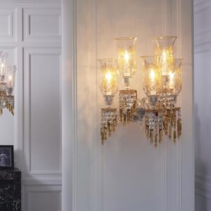 Z√âNITH wall sconce CHARLESTON. Chandeliers, floor candelabra and sconces are adorned with ‚Äúchampagne draped-prisms‚Äù reminding us long pearl necklaces, draped dresses of Charleston dancers. This collection also pays tribute to the creations of Georges Chevalier, his boldness and genius in particular through Jets d‚Äôeau collection. The latter is also in the history of the Maison Baccarat and its private mansion. Indeed, Marie-Laure de Noailles, the owner of this place during this period, was actively involved in the expansion of this movement conducive to creativity, art and renewal. In this spirit the Charleston chandelier has been chosen to adorn the first Baccarat Hotel in New York. The color is a main element in the creation of this new collection.