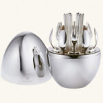 MOOD Party by Christofle. Designed for one's informal dining moments, MOOD Party by Christofle is a set featuring cutlery for 6 people for life's sweet & savory moments. The set includes the following: 6 butter knives, 6 small spoons, 6 appetizer/dessert forks, 6 silver-plated cocktail picks, 1 storage capsule. The egg-shaped storage capsule is made of a mirror-polished steel with a walnut base interior. Christofle shakes up the art of entertaining with a new concept that reflects the current zeitgeist. MOOD Party by Christofle, with its avant-garde vision of convenience and comfort, invites itself to all tables as a promise of sharing and memories.